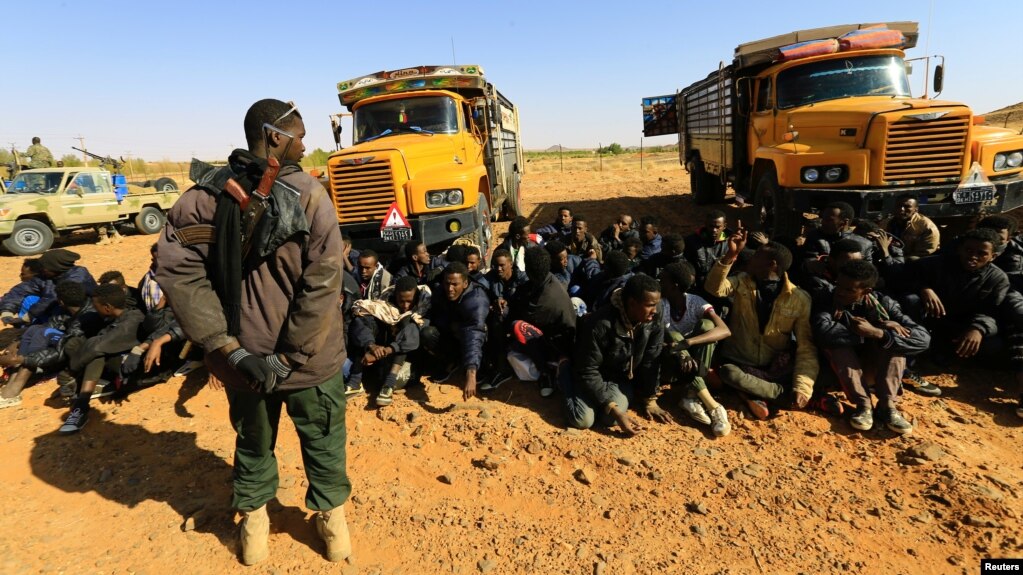 FILE - A member of Sudan's Rapid Support Forces (RSF) stands guard near illegal immigrants and traffickers, who according to the RSF were caught in a remote desert area en route to Libya, in Omdurman, Sudan January 8, 2017. 