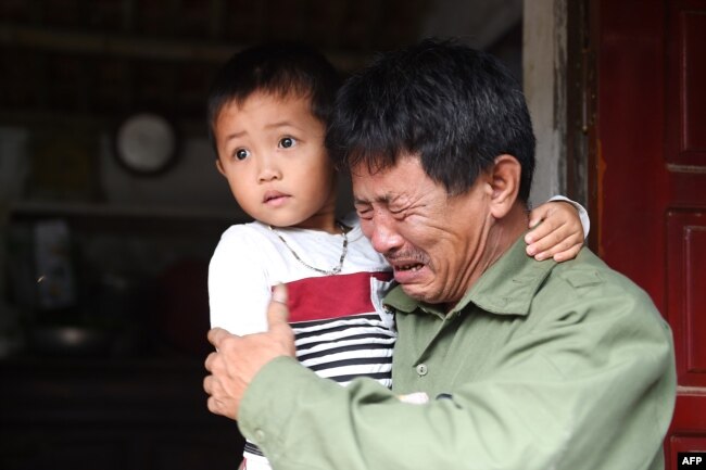 Ölənlərin arasında olduğu güman edilən 30 yaşlı Le Van Hanın atası Le Minh Tuan qucağında Hanın oğlunu tutub. Nghe An vilayəti, Vyetnam. 27 oktyabr, 2019.