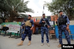 Iraqi security forces stand guard outside a polling station during the parliamentary election in the Sadr city district of Baghdad, May 12, 2018.