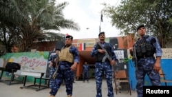 Iraqi security forces stand guard outside a polling station during the parliamentary election in the Sadr city district of Baghdad, May 12, 2018.هێزەکانی ئاسایشی عێراق لە کاتی پاسەوانی لە دەرەوەی بنکەیەکی دەنگدان لە بەغدا، ١٢ی مانگی ٥ی ٢٠١٨