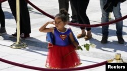A child in a Supergirl costume pays respects as Justice Ruth Bader Ginsburg lies in repose under the Portico at the top of the front steps of the U.S. Supreme Court building, in Washington, U.S. September 23, 2020.