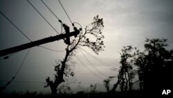 FILE - In this Oct. 16, 2017 file photo, power lines lay broken after the passage of Hurricane Maria in Dorado, Puerto Rico. Federal officials said on Jan. 8 2018, that efforts to fully restore power to Puerto Rico should get a boost with more work crews and more equipment arriving in upcoming weeks. 