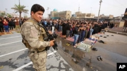 A member of the Iraqi security forces stands guard as worshippers conduct open-air Friday prayers in Baghdad's Sadr City, Iraq, Oct. 30, 2015.