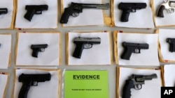 FILE - Chicago police display some of the thousands of illegal firearms confiscated in 2014 in their battle against gun violence, July 7, 2014.