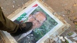 Një demostrues shkel mbi portretin e presidentit Michel Aoun,