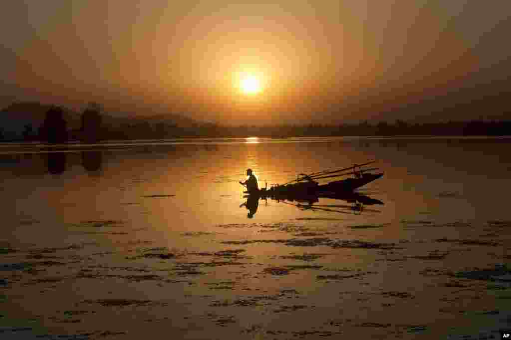 Seorang nelayan Kashmir di atas perahunya saat matahari terbenam di danau Dal, Srinagar, Kashmir-India.