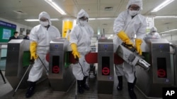 Workers wearing protective gears spray disinfectant as a precaution against the new coronavirus at a subway station in Seoul, South Korea, Friday, Feb. 28, 2020. (AP Photo/Ahn Young-joon)
