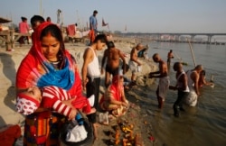 A Hindu woman carries her child as she performs rituals on Ashtami, the eighth day of Navratri festival at Sangam. This is where the Ganges and Yamuna rivers meet in Prayagraj, India, April 1, 2020.