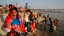 A Hindu woman carries her child as she performs rituals on Ashtami, the eighth day of Navratri festival at Sangam. This is where the Ganges and Yamuna rivers meet in Prayagraj, India, April 1, 2020.
