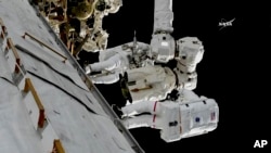 In this frame from NASA TV, astronauts Mark Vande Hei and Randy Bresnik, bottom, work on the International Space Station, Oct. 5, 2017.