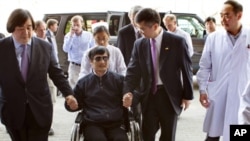 In this photo released by the U.S. Embassy Beijing Press Office, blind lawyer Chen Guangcheng is wheeled into a hospital by U.S. Ambassador to China Gary Locke, right, and an unidentified official at left, in Beijing, May 2, 2012. 