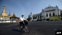 A man wearing a face mask rides a bike on an empty road, 
