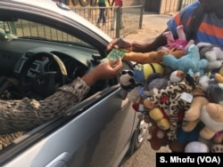 A vendor sells dolls at an intersection of Harare's streets, Oct. 2017.