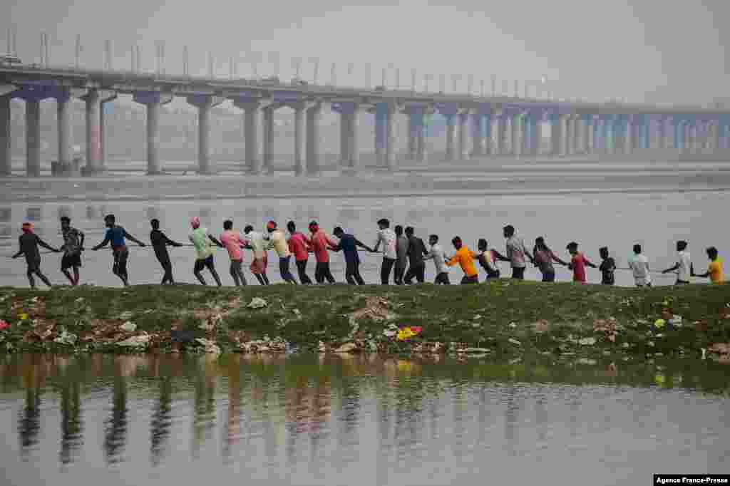 Workers pull a rope connected to a pontoon buoy on the banks of river Ganges to build a floating pontoon bridge as a part of preparations for the yearly Hindu religious fair of Magh Mela in Allahabad, India.