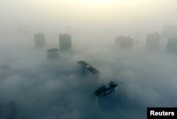 FILE - Buildings are seen on a hazy day in Xiangyang, Hubei province, China, Dec. 31, 2016.