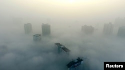 FILE - Buildings are seen on a hazy day in Xiangyang, Hubei province, China, Dec. 31, 2016.