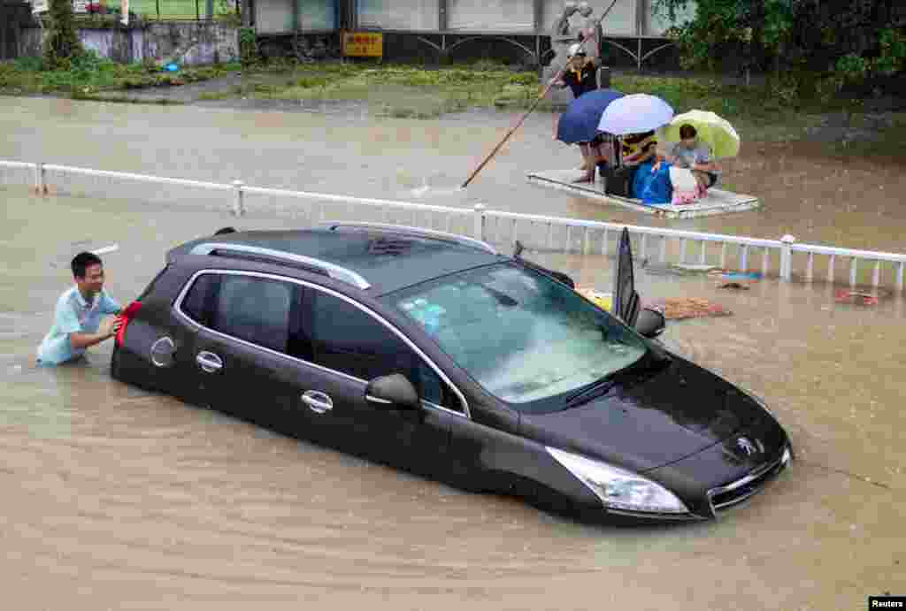 A trapped car is pushed along a flooded street after typhoon Soudelor hit Fuzhou, Fujian province, China.The typhoon battered China&#39;s east coast, killing eight people and forcing authorities to cancel hundreds of flights and evacuate more than 163,000 people.