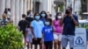 Satu keluarga mengenakan masker saat berjalan-jalan di Miami Beach, Florida, 29 Juni 2020.