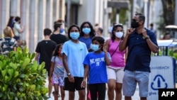 Satu keluarga mengenakan masker saat berjalan-jalan di Miami Beach, Florida, 29 Juni 2020.