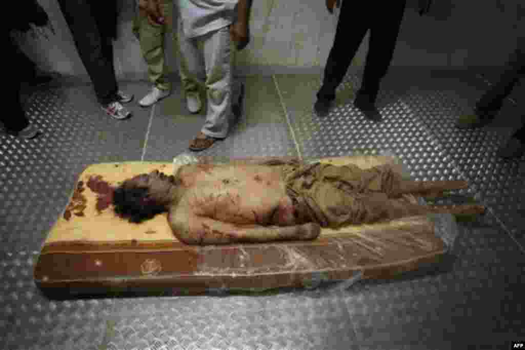 The body of Libyan dictator Moammar Gadhafi lies on a mattress in a commercial freezer at a shopping center in Misrata, Libya, Friday, Oct. 21, 2011. The burial of slain leader Moammar Gadhafi has been delayed until the circumstances of his death can be f