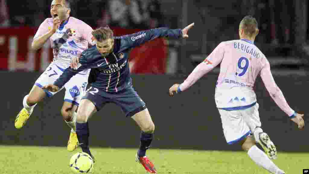 David Beckham (C) of Paris St-Germain challenges Youssef Adnane (L) of Evian Thonon Gaillard to receive a red card during their French Ligue 1 soccer match in Annecy April 28, 2013.