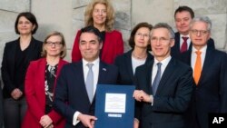 NATO Secretary General Jens Stoltenberg, 3rd right, and Macedonia's Foreign Minister Nikola Dimitrov, 3rd left, pose for photographers with NATO permanent representatives after they signed the "accession protocol" at NATO headquarters in Brussels, Feb. 6, 2019. 