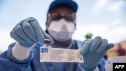 Les infirmières travaillant avec l'Organisation mondiale de la santé montrent une bouteille contenant le vaccin dans la ville de Mbandaka, en RDC, le 21 mai 2018.