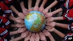 FILE - Students pose for a photo with a globe during a campaign to mark the Earth Day in a middle school in Dexing, Jiangxi province, China.