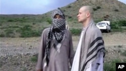 In this image taken from video obtained from Voice Of Jihad Website, which has been authenticated based on its contents and other AP reporting, Sgt. Bowe Bergdahl, right, stands with a Taliban fighter in eastern Afghanistan. 