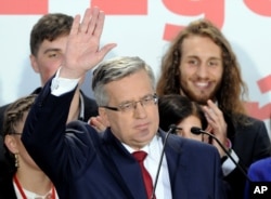 Polish President Bronislaw Komorowski waves to supporters as first exit polls are announced in Warsaw, Poland, May 24, 2015.