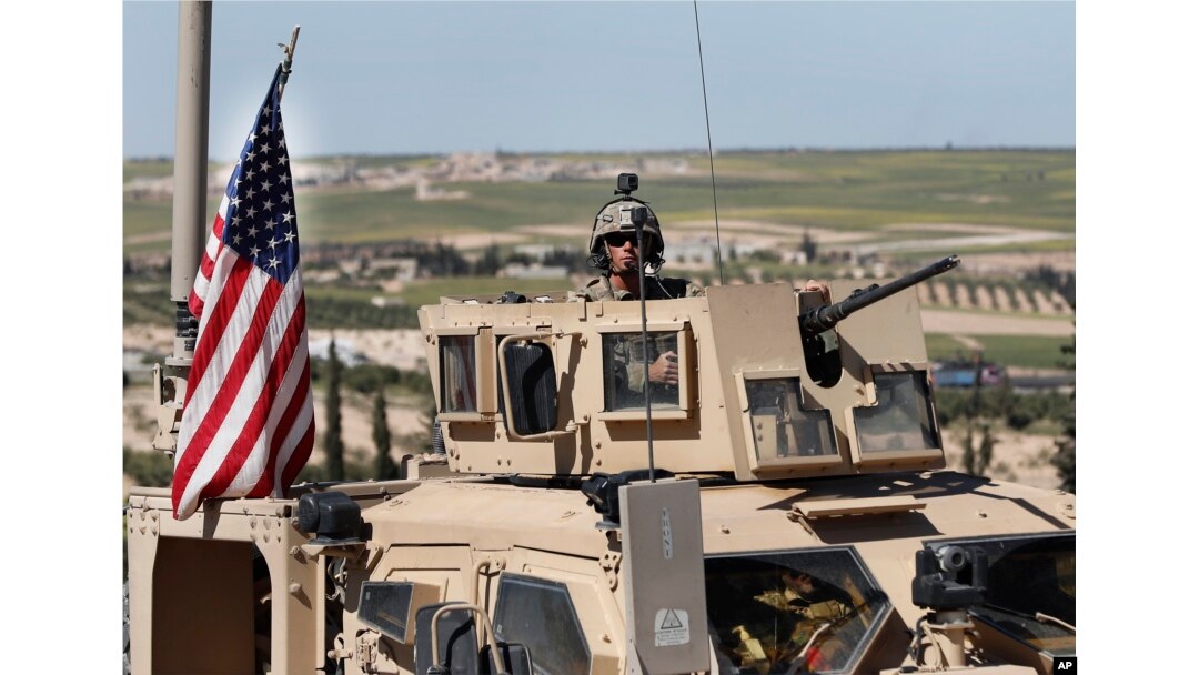 FILE - A U.S. soldier sits atop an armored vehicle, in Manbij, Syria, April 4, 2018.