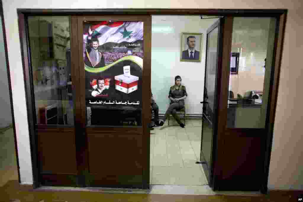 Seorang tentara Suriah duduk di bawah potret Presiden Bashar al-Assad di tempat pemilihan di Damascus, 3 Juni 2014.