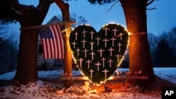 FILE - A makeshift memorial with crosses for the victims of the Sandy Hook Elementary School shooting massacre stands outside a home in Newtown, Conn., on the one-year anniversary of the shootings, Dec. 14, 2013. 