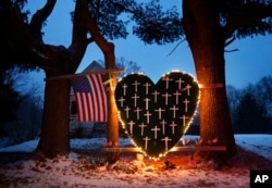 FILE - A makeshift memorial with crosses representing the victims of the Sandy Hook Elementary School shooting massacre stands outside a home in Newtown, Connecticut, on the first anniversary of the shooting, Dec. 14, 2013.