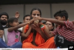 FILE - Indian yoga guru Baba Ramdev drinks a fruit juice offered by children to break his fast in New Delhi, India, August 14, 2012.