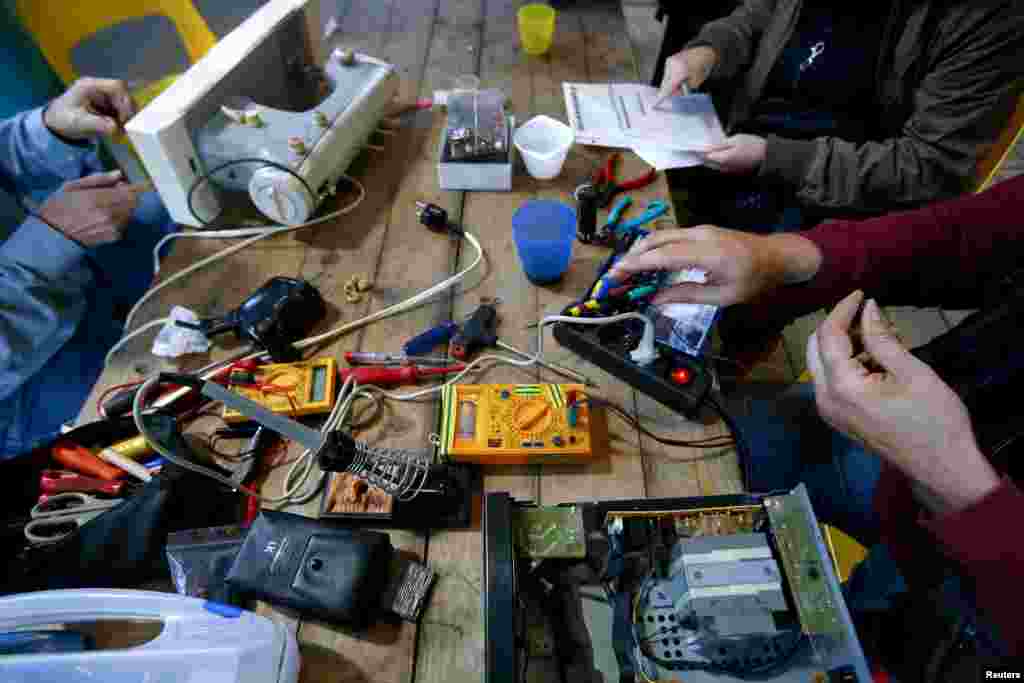 People work on non-functioning electrical items at a so-called 'Repair Cafe' in Berlin's Kreuzberg district, Germany.