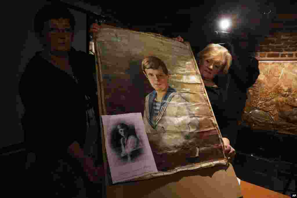 Larisa Bordovskaya, chief curator, right, and Iraida Botti, deputy director of Yekaterininsky Palace Museum, display a portrait of a boy, who is believed to be Prince Alexei Romanov, in Yekaterininsky Palace in the Tsarskoye Selo, suburb of St.Petersburg, Russia.