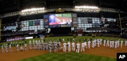 Members of the military throw out ceremonial first pitches to both teams before a baseball game between the Milwaukee Brewers and the Minnesota Twins in Milwaukee, May 27, 2013.