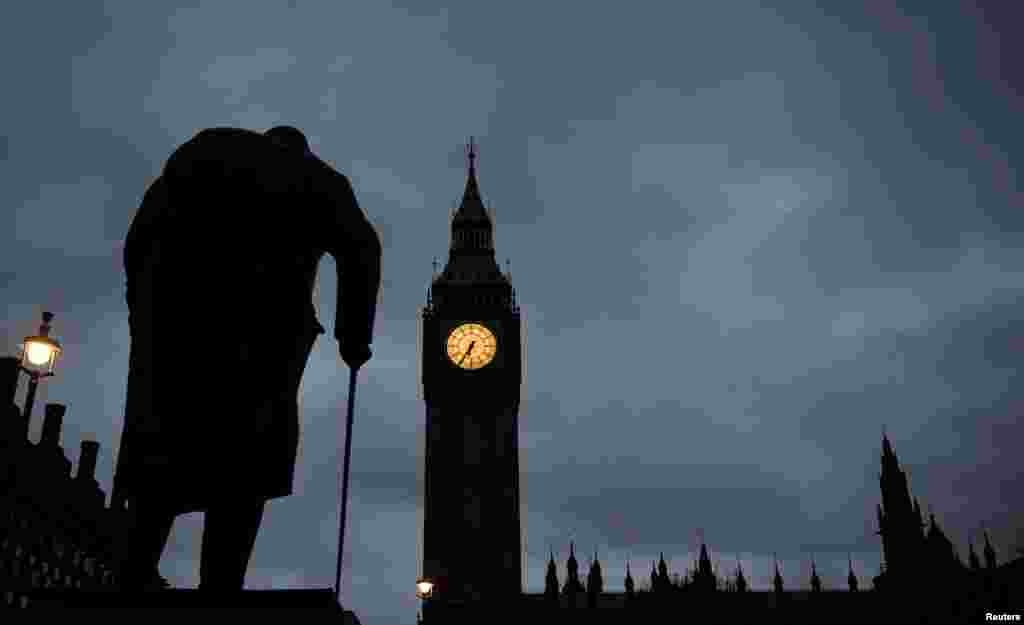 Siluet patung Winston Churchill terlihat di depan jam Big Ben dan gedung parlemen di London, Inggris.