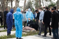 Virus Outbreak Mideast Iran -- Relatives mourn over the body of Fatemeh Rahbar, a lawmaker-elect from a Tehran constituency, who died on Saturday after being infected with the new coronavirus, at Behesht-e-Zahra cemetery, just outside Tehran, Iran, Sunday