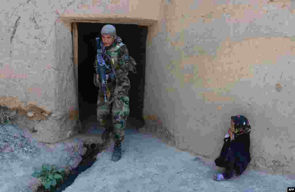 A girl watches an Afghanistan National Army (ANA) special forces soldier as he patrols in Gozara District of Herat.