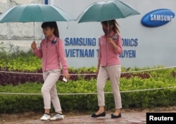FILE - An employee (L) holds a smartphone as she is on the way to work at the Samsung factory in Thai Nguyen province, north of Hanoi, Vietnam, Oct. 13, 2016.