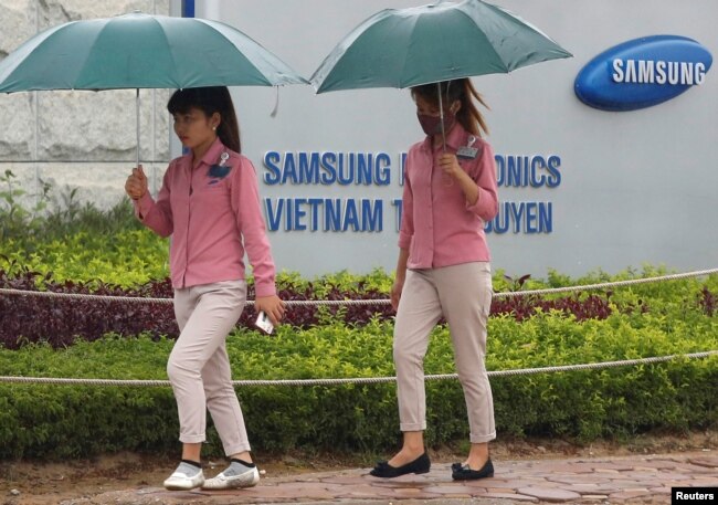 FILE - An employee (L) holds a smartphone as she is on the way to work at the Samsung factory in Thai Nguyen province, north of Hanoi, Vietnam, Oct. 13, 2016.