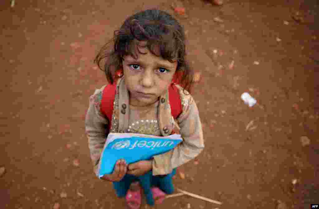 A Syrian child who fled with her family from the northern countryside of Hama, holds a book in the yard of the makeshift school of &quot;Zuhur al-Mustaqbal&quot; (in Arabic &quot;Flowers of the Future&quot;) in al-Jeneinah camp for displaced people in the village of Atme, in Syria&#39;s mostly rebel-held northern Idlib province.