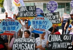 FILE - Protesters display placards during a rally at the Chinese Consulate to protest China's artificial island-building at the disputed islands, reefs and shoals off South China Sea, June 12, 2017 at the financial district of Makati city, east of Manila, Philippines.