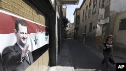 A woman passes a poster in support of President Assad, Damascus, September 15, 2011.