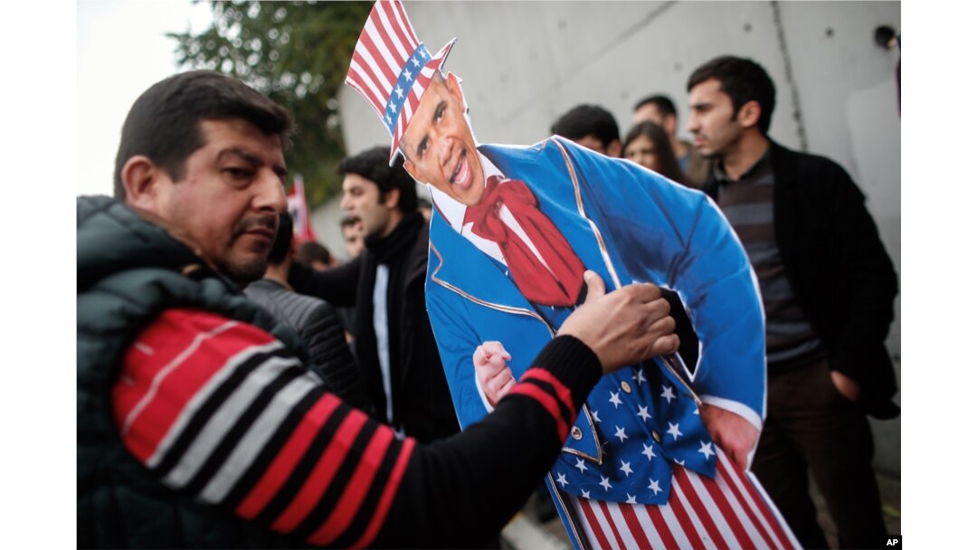 Plainclothes police officers take away an effigy of President Barack Obama as members of the Turkey Youth Union gather to protest the upcoming visit of Obama to Turkey in mid-November for G20 summit in Antalya, outside the US consulate in Istanbul, Nov. 8, 2015.