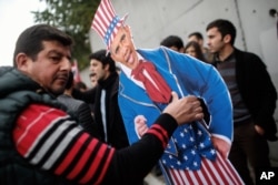 Plainclothes police officers take away an effigy of President Barack Obama as members of the Turkey Youth Union gather to protest the upcoming visit of Obama to Turkey in mid-November for G20 summit in Antalya, outside the US consulate in Istanbul, Nov. 8, 2015.