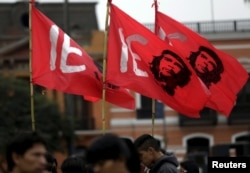 FILE - Protesters holding flags bearing the image of Che Guevara march during a mining national strike in Lima, May 21, 2015.