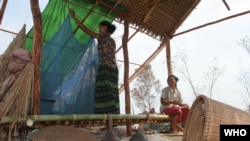 A Cambodian woman hangs her mosquito net in the temporary dwelling in the fields that she and her husband are clearing to farm.